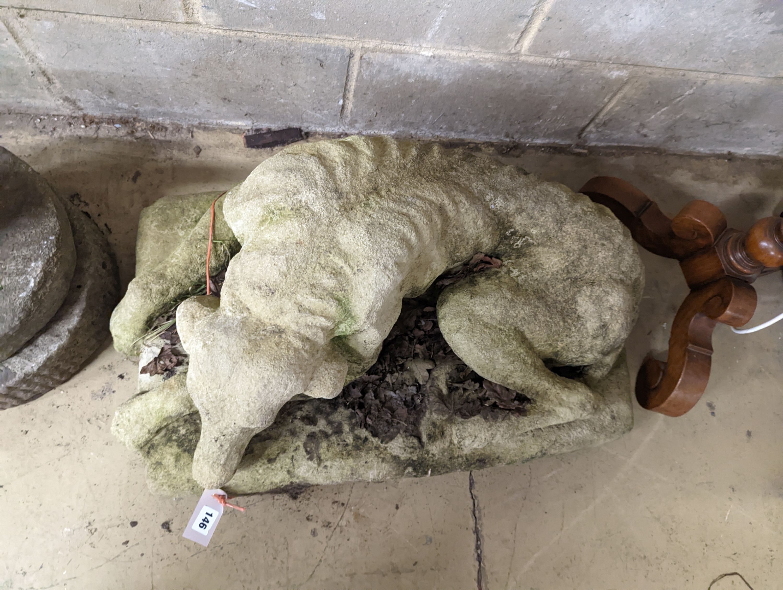 A reconstituted stone recumbent hound garden ornament, width 80cm, depth 42cm, height 44cm